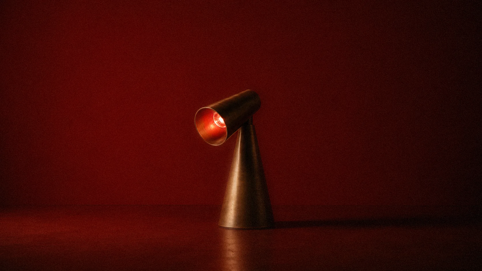 Milieu Table Lamp 001 lit red against a deep red wall